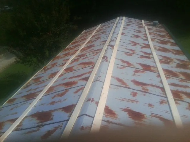 Rusted metal roof panels with new wood purlins before replacement — Storm Damage Roof Repair in Whitt by Roofing Brothers