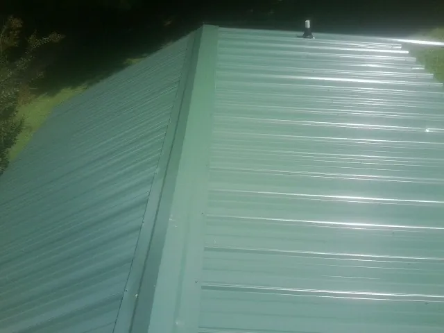 New green metal panels meeting at the ridge of a roof — Flat Roof Repair work by our crew in Whitt