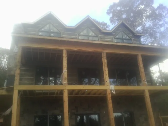 Dormers and porch framing on a large log home under construction — Roof Coating work by our crew in Whitt