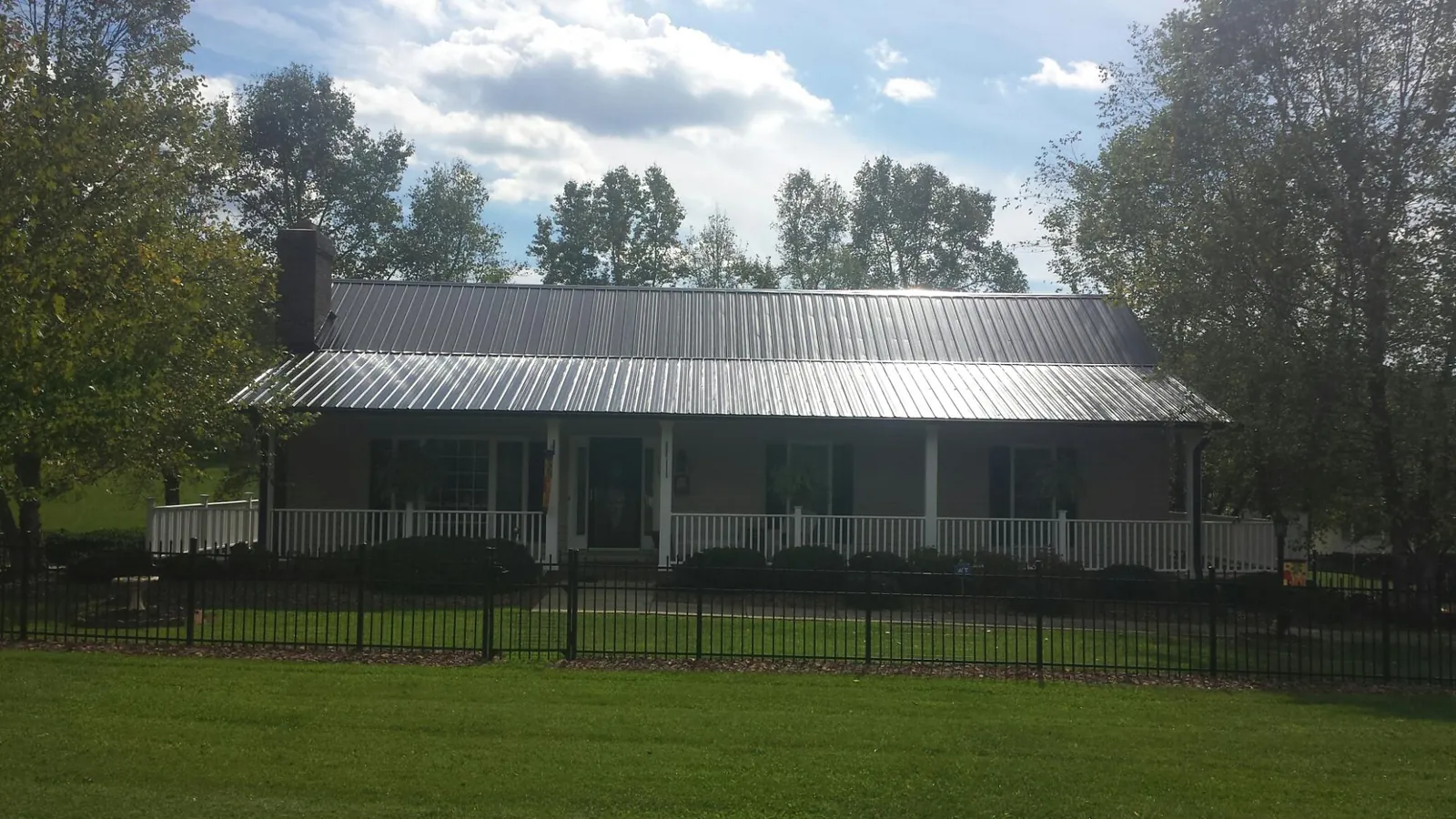 Gray metal roof on a brick ranch with a full width front porch — Gutter Guard Installation work by our crew in Whitt